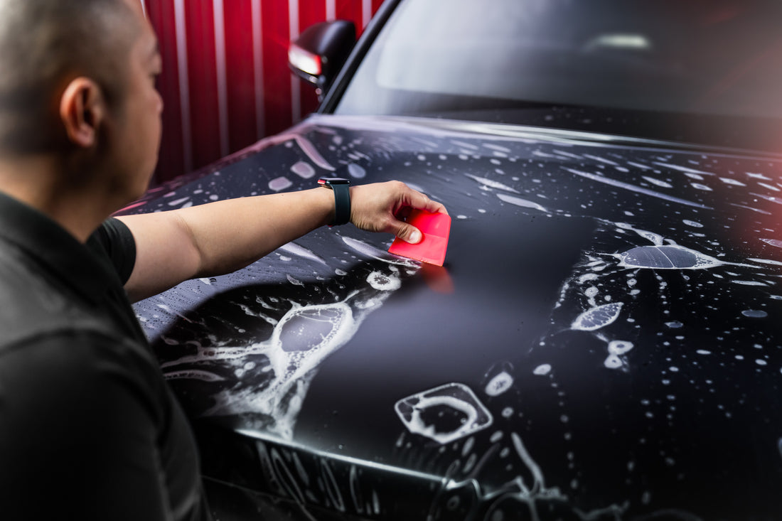 installer applying squeegee tool to ppf on hood of car