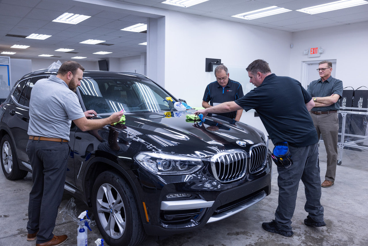 Installation training, four men working on a car