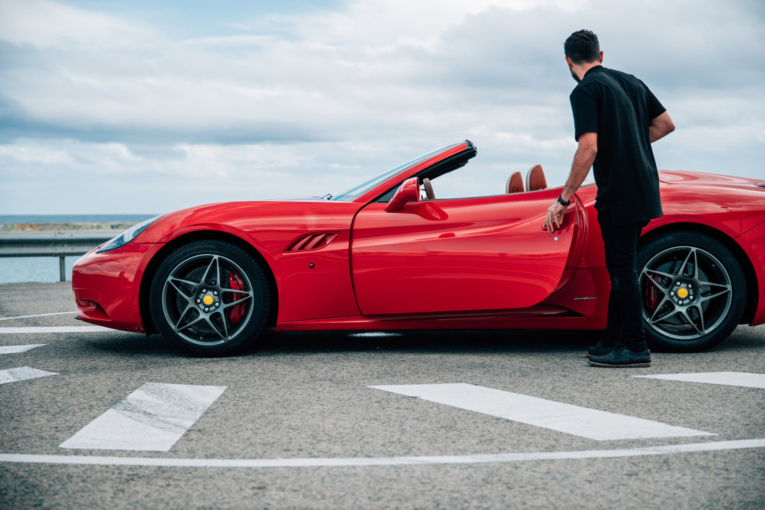 Man getting into red convertible sports car