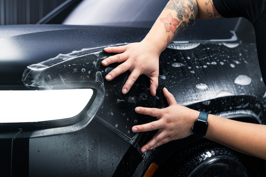 installer's hands applying paint protection film to side of car hood
