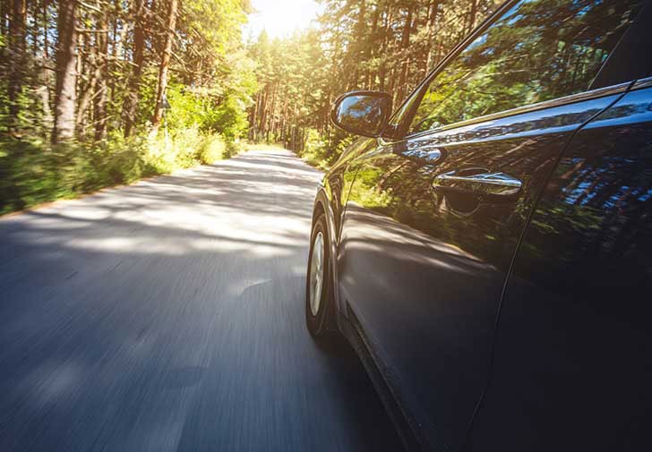 view of car cruising down a wooded road